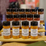 PSC Zestful, Cajun, and Smoked Hickory BBQ seasoning bottles on display at trade show booth with SQF certified site sign